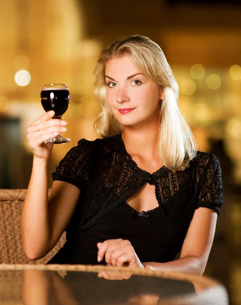 Hermosa joven bebiendo vino tinto en un restaurante — Foto de Stock