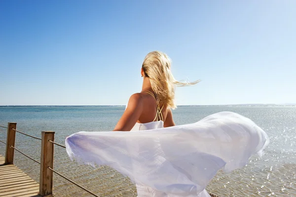Blond kvinna med vit sjalen avkopplande nära havet — Stockfoto