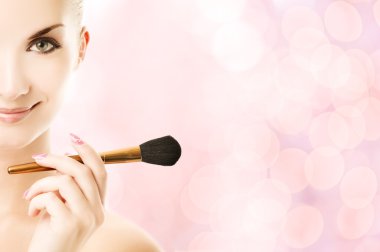 Lovely young woman with a make-up brush clipart