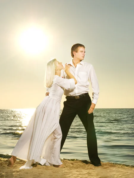 Молода пара танцює на пляжі на заході сонця — стокове фото