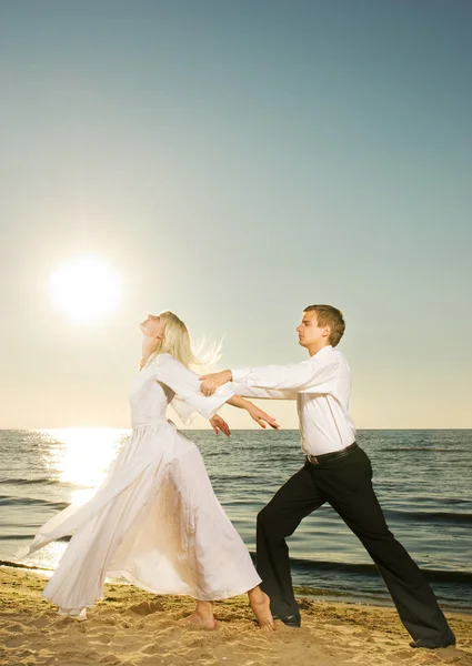 日落黄昏的海滩上跳舞的年轻夫妇 — 图库照片