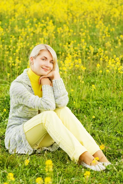 Красива молода жінка сидить у квітковому полі — стокове фото