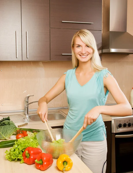 Beautiful young woman mixing vegetable salad in a glass bowl — Stock Photo, Image