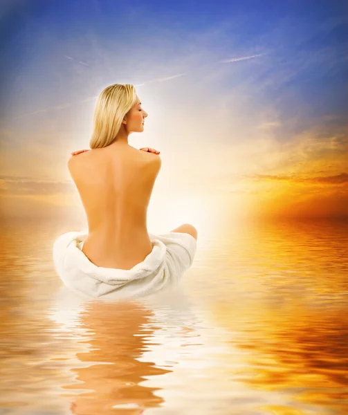 Красива молода жінка розслабляється біля моря на заході сонця — стокове фото