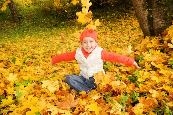 Красива маленька дівчинка з осіннім листям на відкритому повітрі — стокове фото