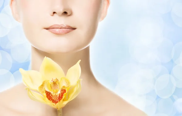 Beautiful woman with yellow orchid over abstract blue background — Stock Photo, Image