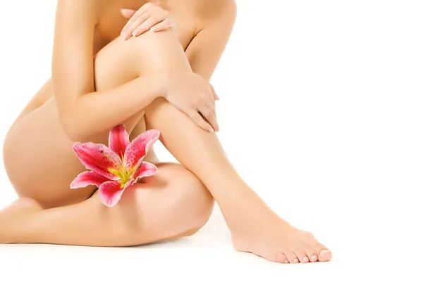 Weibliche Beine mit rosa Lilie isoliert auf weißem Hintergrund — Stockfoto