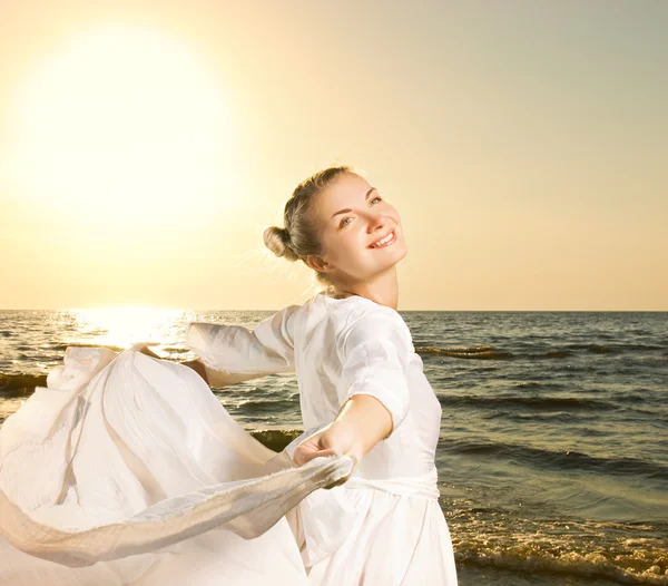 美丽的年轻女子在日落时在沙滩上跳舞 — 图库照片