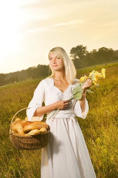 焼きたてのパンがいっぱい入ったかごを持つ美しい若い女性 — ストック写真