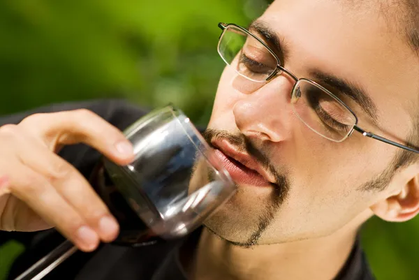 Красивый молодой человек пьет красное вино — стоковое фото