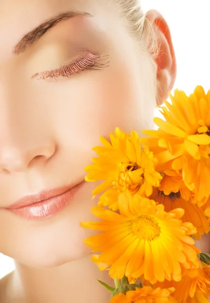 Vacker ung kvinnas ansikte med orange blommor — Stockfoto