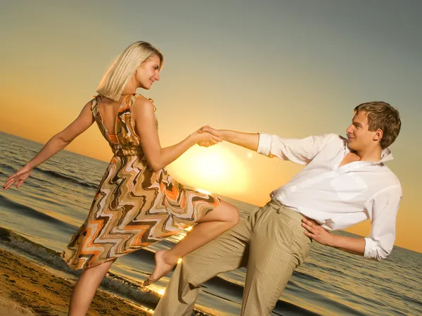 日落时一对年轻夫妇在海边跳舞 — 图库照片