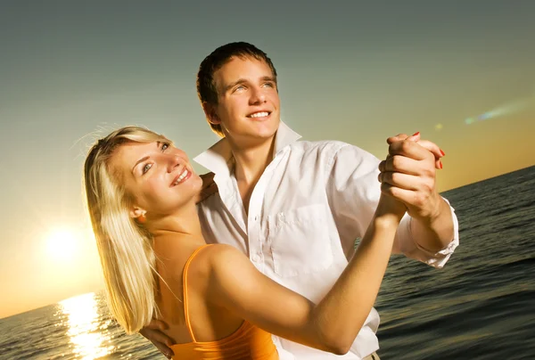 日落时一对年轻夫妇在海边跳舞 — 图库照片