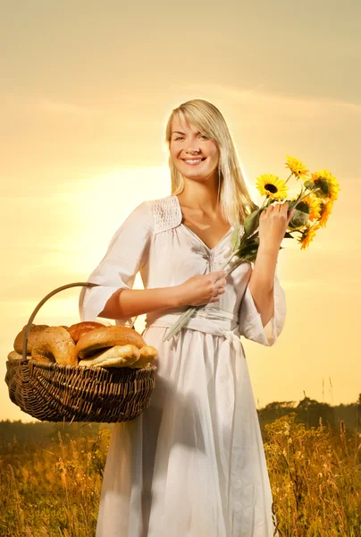 Vacker ung kvinna med en korg full av nybakat bröd — Stockfoto