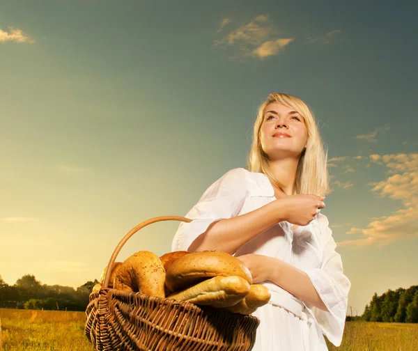 Hermosa joven con una cesta llena de pan recién horneado —  Fotos de Stock
