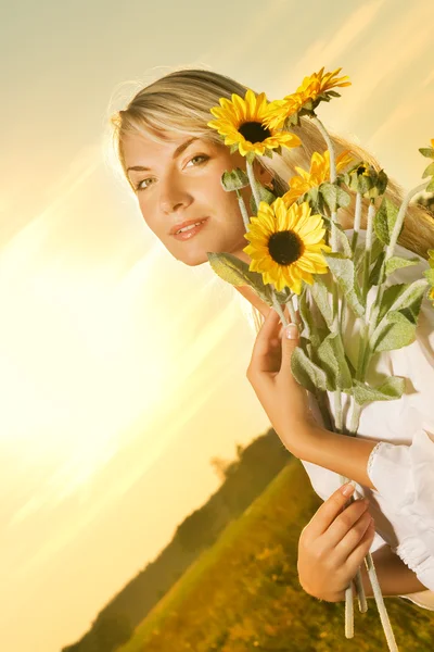 Молода красива жінка з букетом соняшників у полі — стокове фото