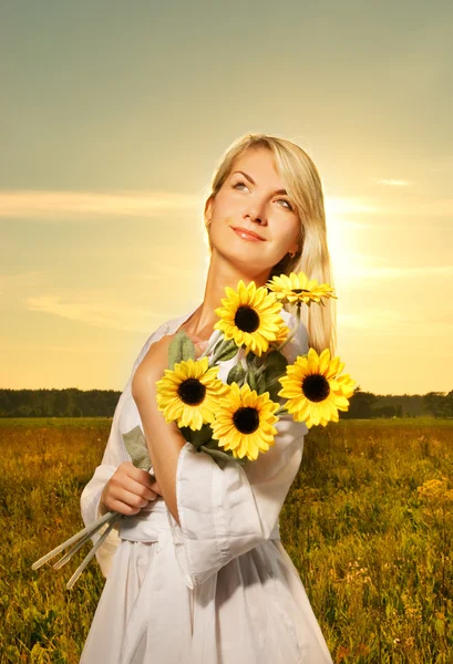 Ung vacker kvinna med en bukett av solrosor i fältet — Stockfoto