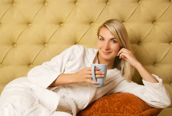 美しい若い女性がベッドの上に座っていると 朝のコーヒーを飲む — ストック写真