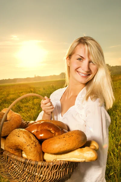 Hermosa joven con una cesta llena de pan recién horneado —  Fotos de Stock