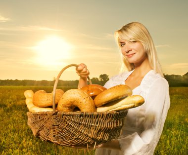 Beautiful young woman with a basket full of fresh baked bread clipart