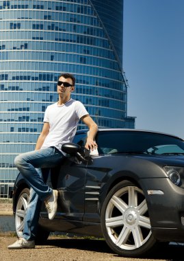 Handsome man standing near the modern sport car clipart