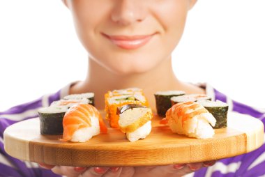 Happy woman holding bamboo plate with fresh sushi set on it (Shallow DoF, focus on sushi) clipart