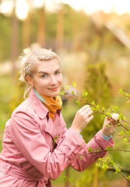 Beautiful woman touching young plant in the garden clipart