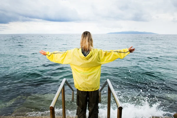 Dappere vrouw groet stormachtige Oceaan — Stockfoto