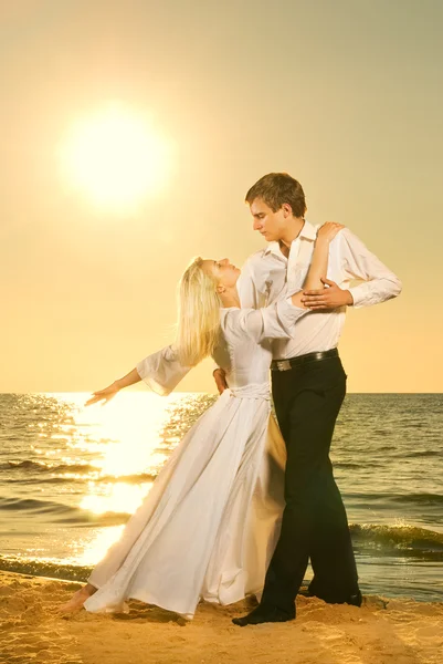 日落黄昏的海滩上跳舞的年轻夫妇 — 图库照片