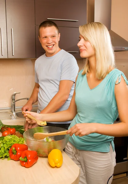 Νεαρό ζευγάρι κάνει σαλάτα λαχανικών στην κουζίνα — Φωτογραφία Αρχείου