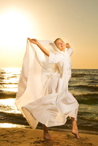 Belle jeune femme sautant sur une plage au coucher du soleil — Photo