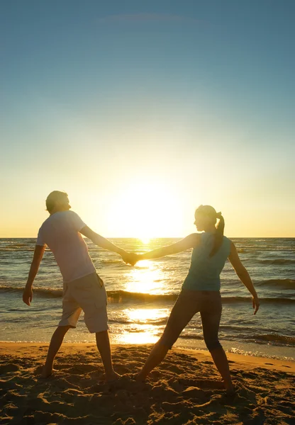 男と女のリラックスした夕日の海を近く — ストック写真