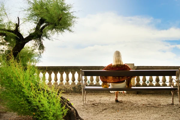 Parkta bir bankta oturan genç kadın — Stok fotoğraf