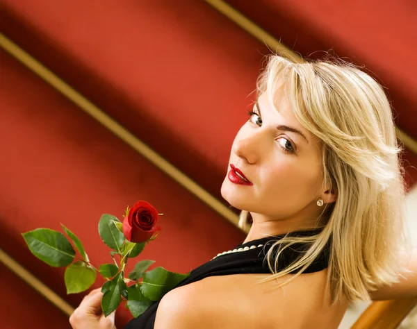 Krásná mladá žena stojící na červeném koberci a drží ros — Stock fotografie