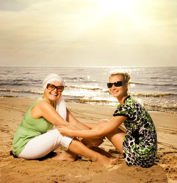Две красивые женщины сидят на пляже — стоковое фото