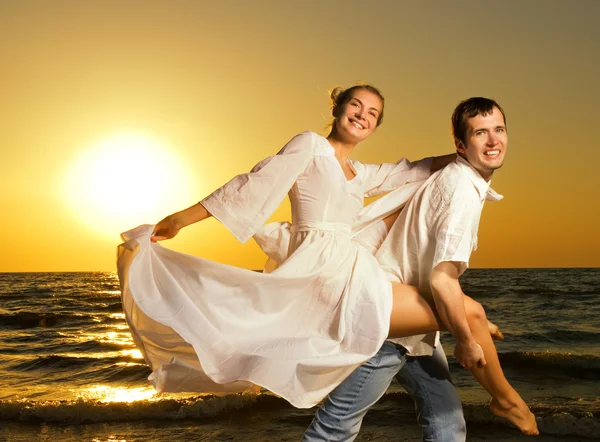 开心的年轻夫妇在日落时附近的海洋 — 图库照片