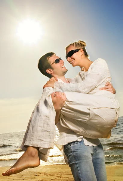 Молодая счастливая пара веселится на пляже — стоковое фото