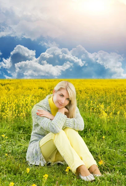 Красивая молодая женщина, сидящая на цветочном поле — стоковое фото