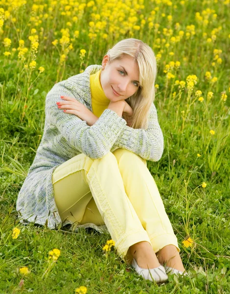 Красивая молодая женщина, сидящая на цветочном поле — стоковое фото
