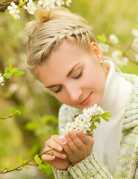 Schöne junge Frau sieht Marienkäfer auf Blumen — Stockfoto