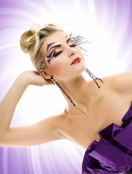 Красивая молодая женщина с художественным макияжем над абстрактным фиолетовым — стоковое фото