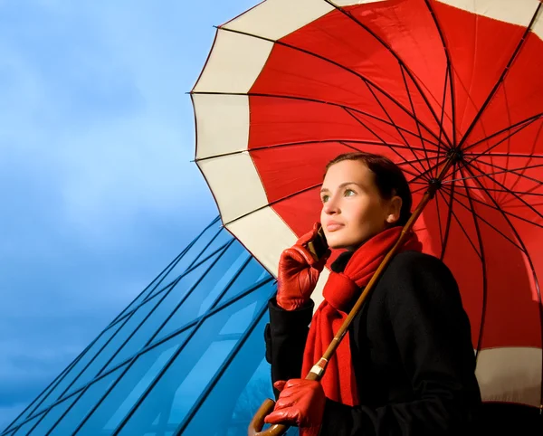携帯電話で話している赤い傘と美しいブルネット — ストック写真