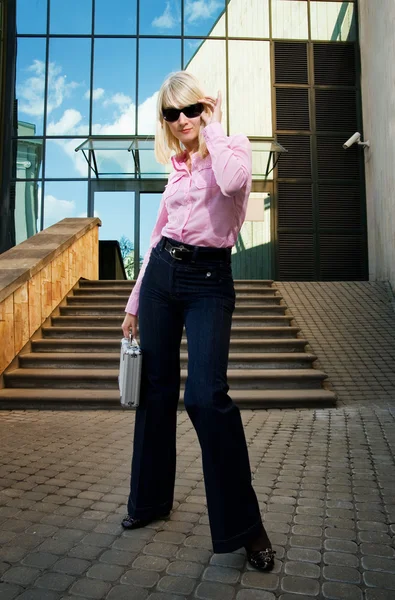 Piękna młoda kobieta ze srebrną walizkę w pobliżu bu nowoczesne biuro — Zdjęcie stockowe