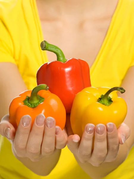 Mulher segurando pimentas coloridas doces em suas mãos — Fotografia de Stock
