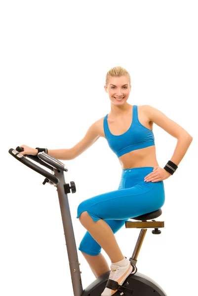 Beautiful young woman on exercise bicycle over white background — Stock Photo, Image