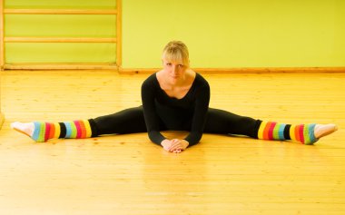 Ballet dancer doing stretching exercise on a floor clipart