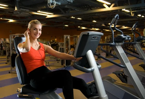 Vacker ung kvinna gör övning i ett gym medan du lyssnar på — Stockfoto