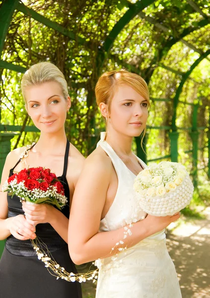 Two girls with a flowers in green alley — Stock Photo, Image