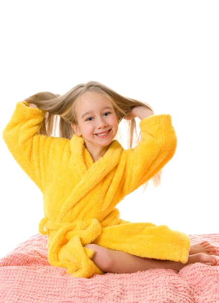 Pretty young girl sitting on a bed and touching her hair — Stock Photo, Image