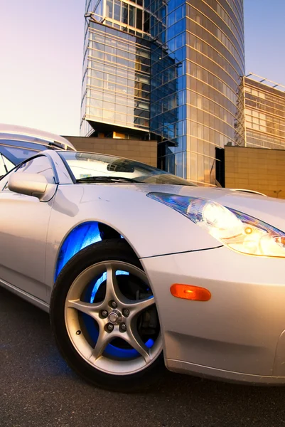 Спортивный автомобиль с офисным зданием и чистым голубым небом позади него — стоковое фото